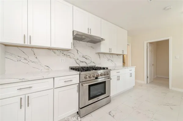 a kitchen with granite countertop white cabinets and white stove