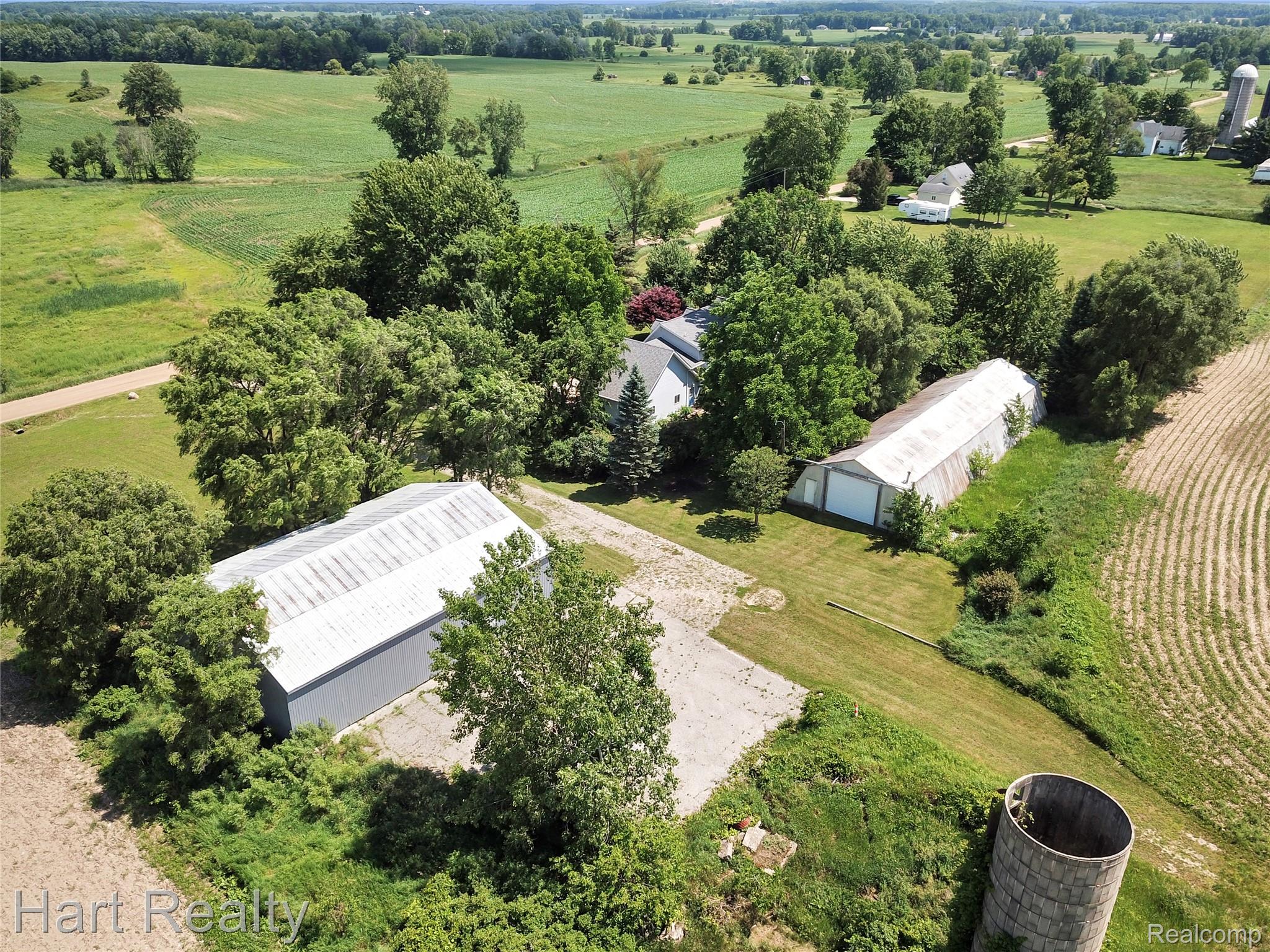 7167 Brown School Road North Branch, MI 48461 - Photo 47 of 51 Aerial view showcasing a residential property amidst expansive green fields, featuring multiple outbuildings, mature trees, and a silo