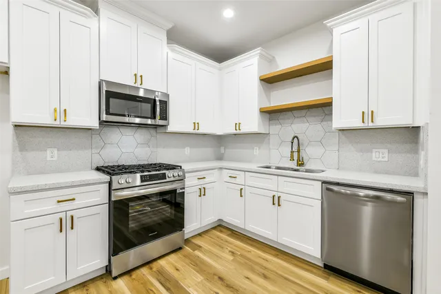 a kitchen with stainless steel appliances granite countertop white cabinets and a stove top oven