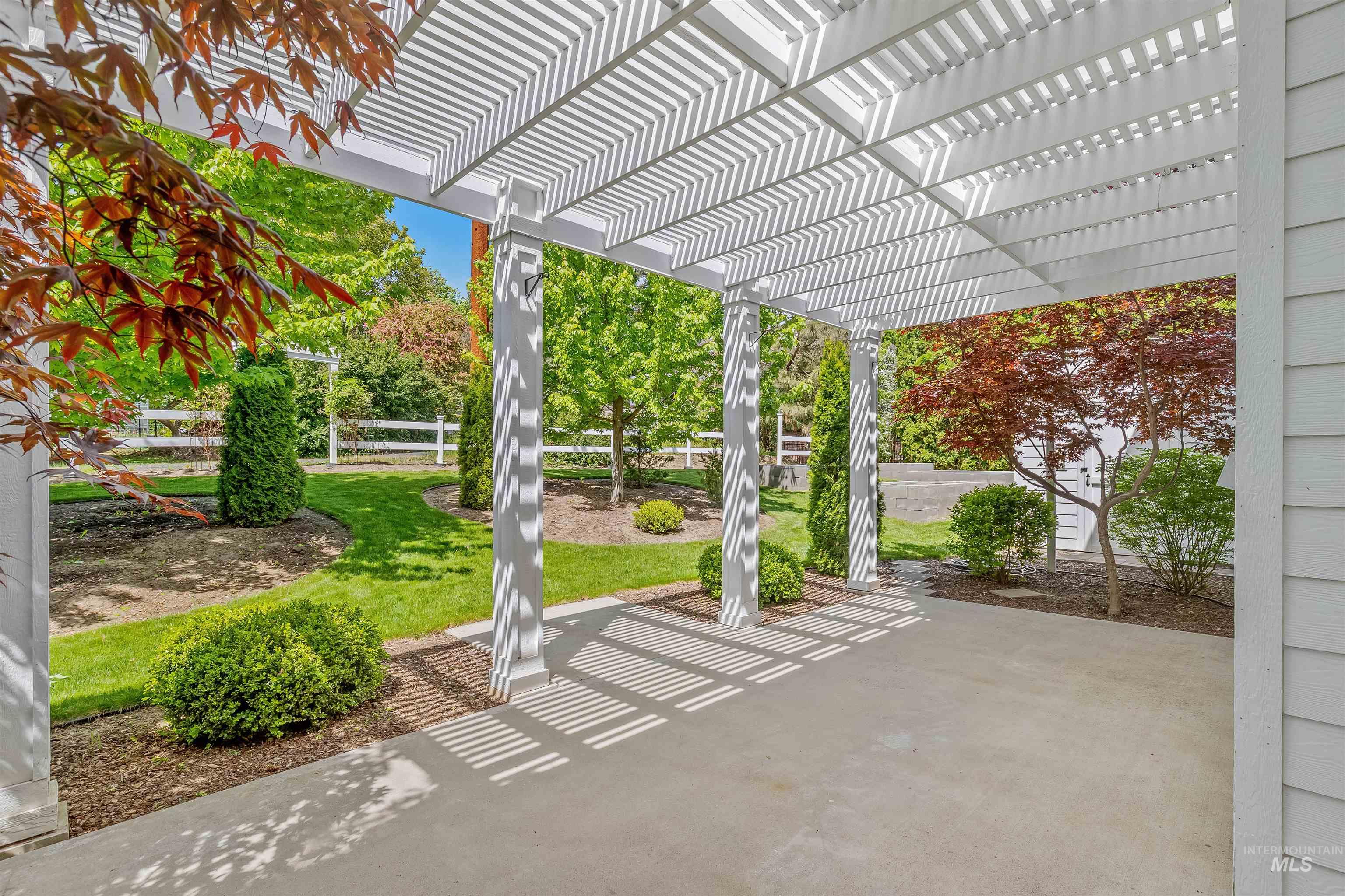 1617 Pine Cone Road Moscow, ID 83843 - Photo 30 of 44 Covered patio featuring a white pergola structure, concrete flooring, and surrounding mature landscaping