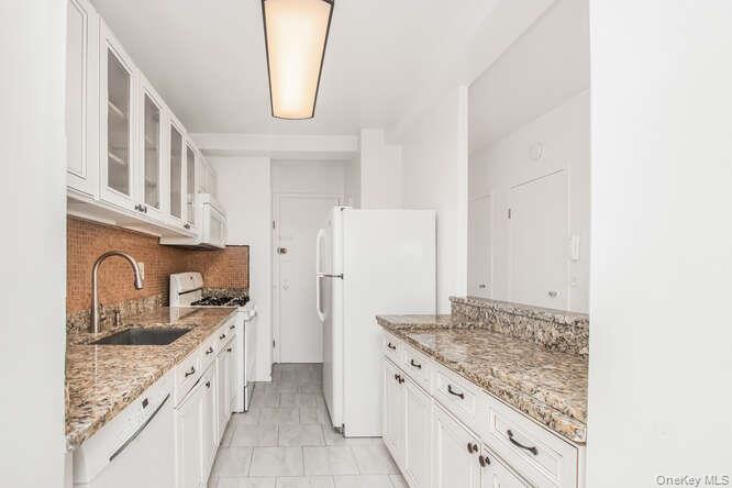 6 Fordham Hill Ovl, Unit 15F Bronx, NY 10468 - Photo 12 of 26 Kitchen with glass insert cabinets, white cabinetry, white appliances, and light stone counters