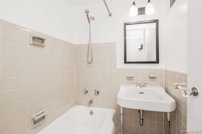 6 Fordham Hill Ovl, Unit 15F Bronx, NY 10468 - Photo 13 of 26 Full bath with bathtub / shower combination, tile walls, and a wainscoted wall