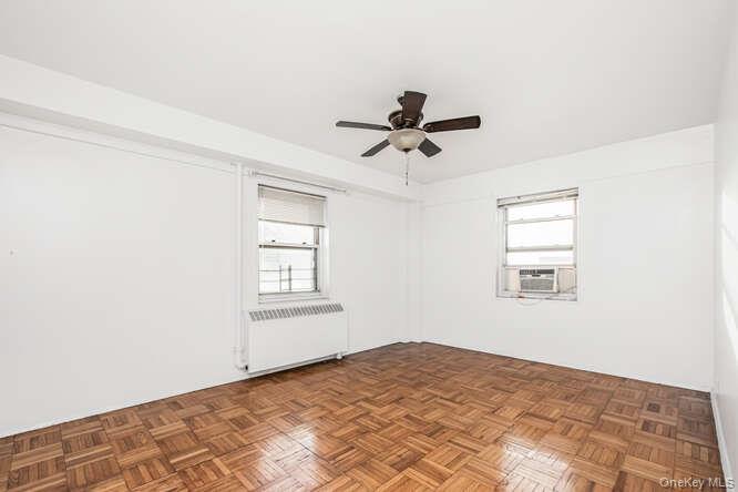 6 Fordham Hill Ovl, Unit 15F Bronx, NY 10468 - Photo 16 of 26 Unfurnished room featuring plenty of natural light, radiator heating unit, and ceiling fan