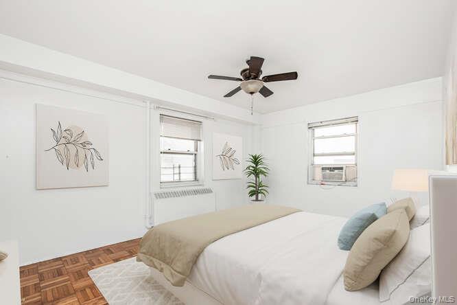 6 Fordham Hill Ovl, Unit 15F Bronx, NY 10468 - Photo 17 of 26 Virtually staged Primary Bedroom featuring multiple windows, a ceiling fan, and radiator heating unit