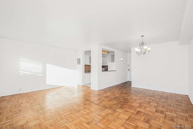 6 Fordham Hill Ovl, Unit 15F Bronx, NY 10468 - Photo 7 of 26 Living room and dining area with a chandelier