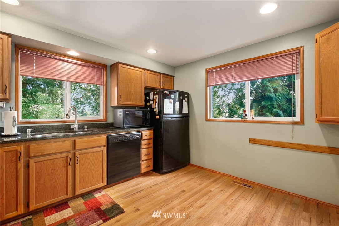 5030 Northeast 21st Street Renton, WA 98059 - Photo 6 of 27 a kitchen with stainless steel appliances granite countertop a refrigerator a sink dishwasher a stove and white countertops with wooden floor