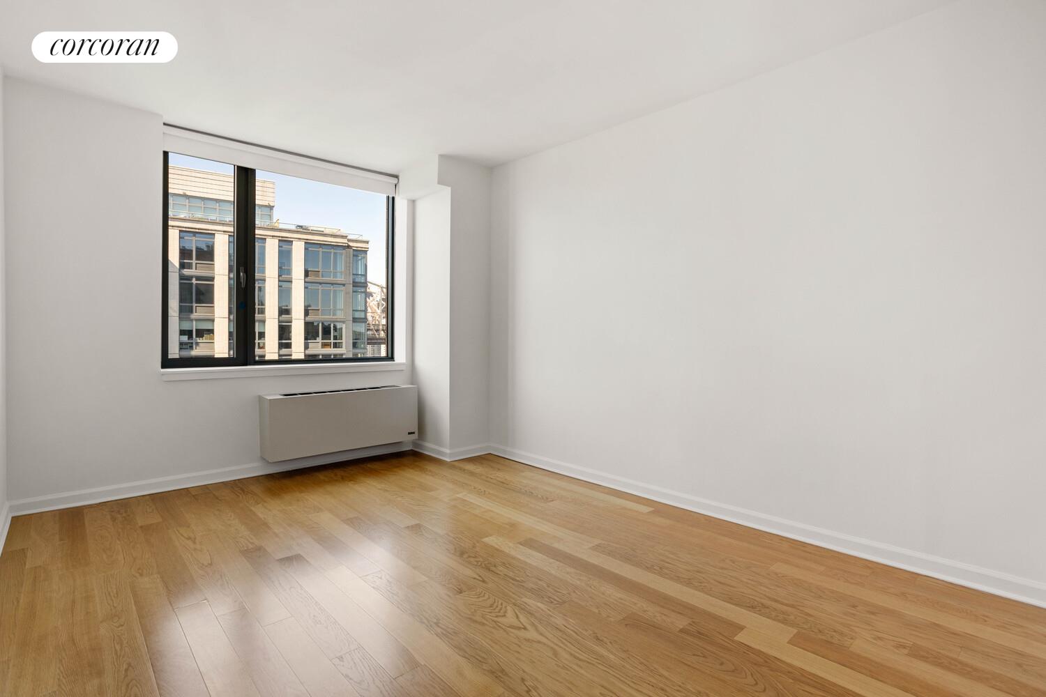 425 Main Street, Unit 15E Manhattan, NY 10044 - Photo 15 of 30 an empty room with wooden floor and windows