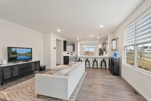 a living room with stainless steel appliances furniture and a flat screen tv