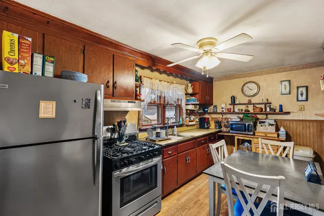 a kitchen with stainless steel appliances granite countertop a refrigerator a sink dishwasher a stove and a dining table with wooden floor