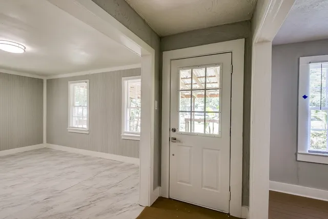 a view of an empty room with wooden floor and a window