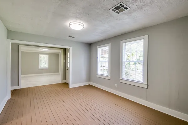 an empty room with wooden floor and windows