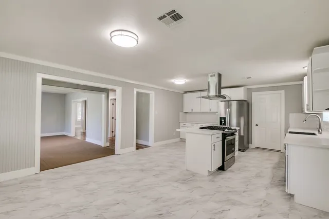 a view of a kitchen with a sink and dishwasher a stove top oven with wooden floor