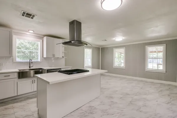 a kitchen with a stove a sink a window and dining table