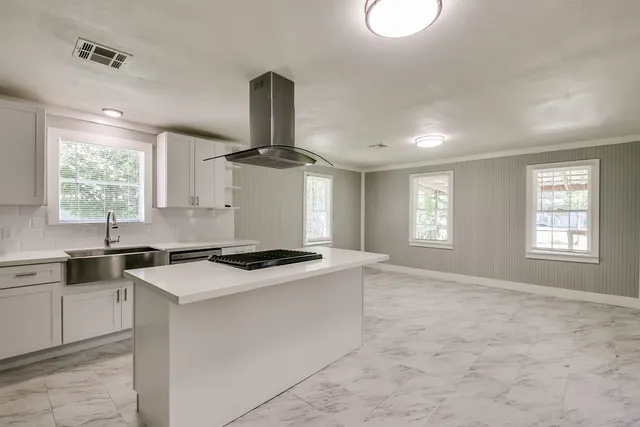 a kitchen with a stove a sink a window and dining table