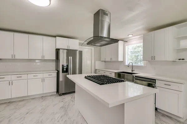 a kitchen with a stove a sink dishwasher a refrigerator and white cabinets with wooden floor