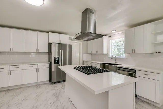 a kitchen with a stove a sink dishwasher a refrigerator and white cabinets with wooden floor