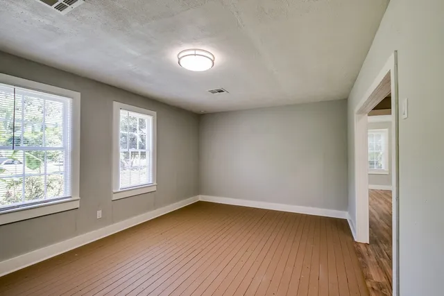 an empty room with wooden floor and windows