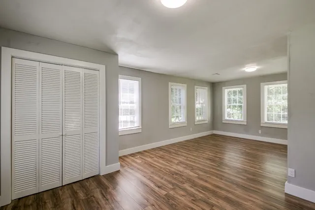 an empty room with wooden floor and windows