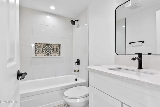 a bathroom with a granite countertop sink a toilet and a bathtub