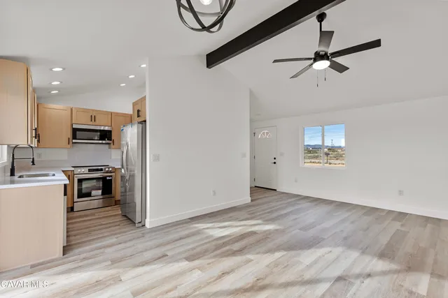 a view of kitchen with stainless steel appliances refrigerator stove microwave and cabinets