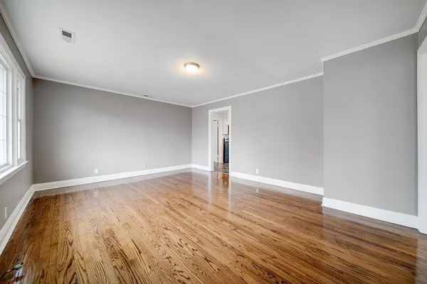 a view of an empty room with wooden floor and window