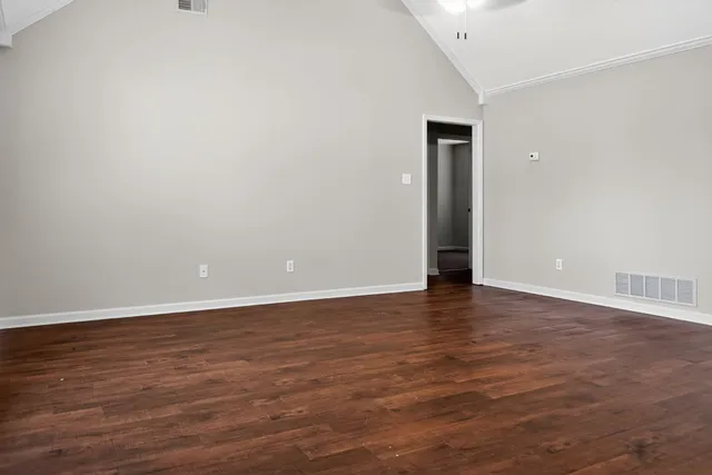 a view of an empty room with wooden floor and closet