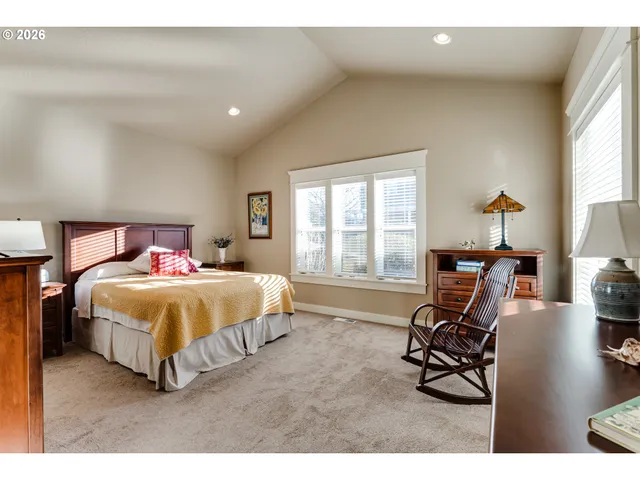 a bedroom with a bed a chair and next to a window