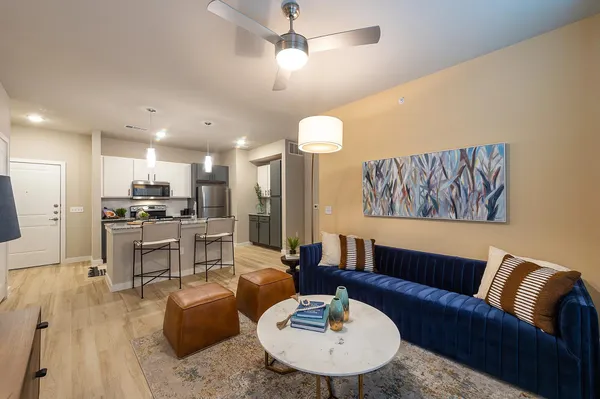 a living room with furniture kitchen view and a chandelier