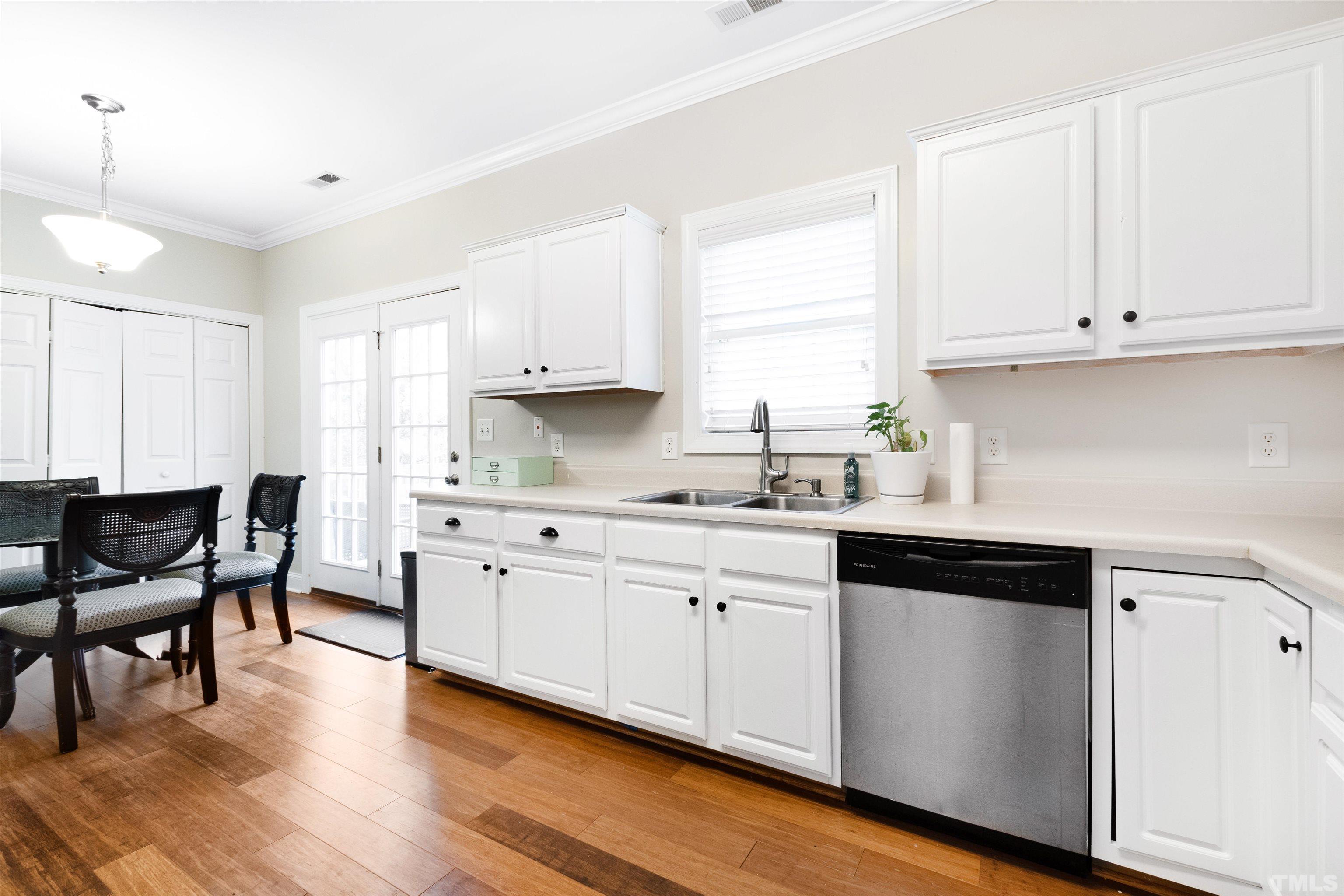4928 Morning Edge Drive Raleigh, NC 27613 - Photo 5 of 25 a kitchen with granite countertop white cabinets white appliances with wooden floors