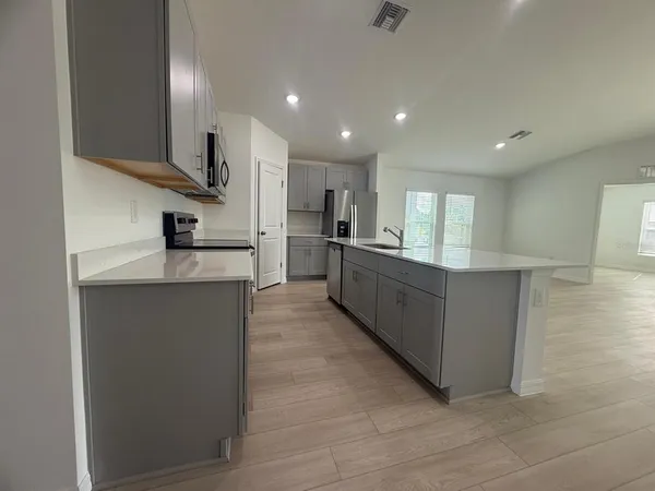 a large kitchen with stainless steel appliances kitchen island granite countertop a large counter top a sink and a stove
