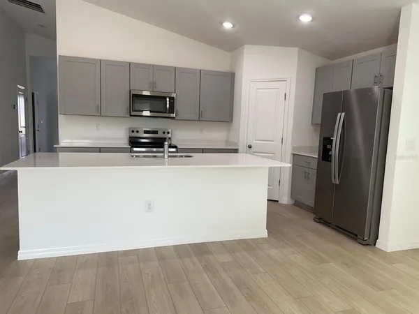 a kitchen with stainless steel appliances granite countertop a refrigerator a stove a sink and a microwave