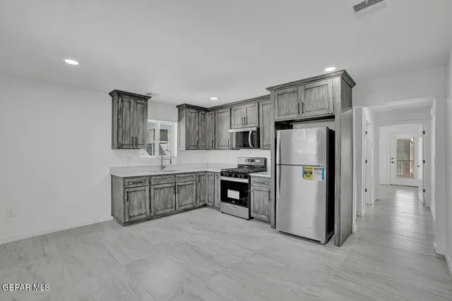 a large kitchen with stainless steel appliances granite countertop a stove a sink and a microwave