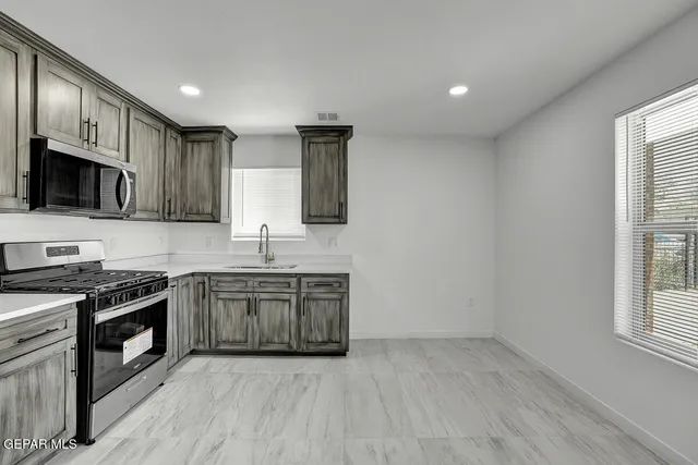 a kitchen with stainless steel appliances granite countertop a refrigerator stove and microwave