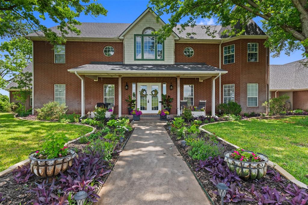 Colonial-style house with french doors, a front yard, brick siding, and a porch