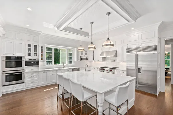 a kitchen with stainless steel appliances a dining table chairs stove and cabinets