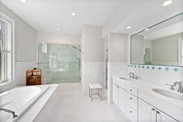 a spacious bathroom with a double vanity sink a toilet a mirror and shower