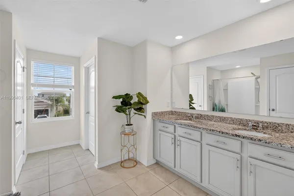 a spacious bathroom with a granite countertop sink a mirror and a bathtub