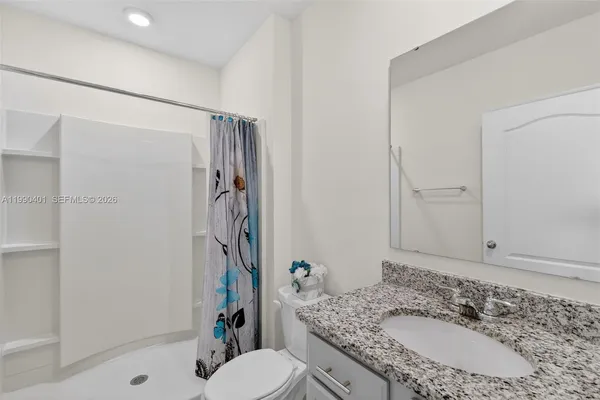 a bathroom with a granite countertop sink toilet and shower