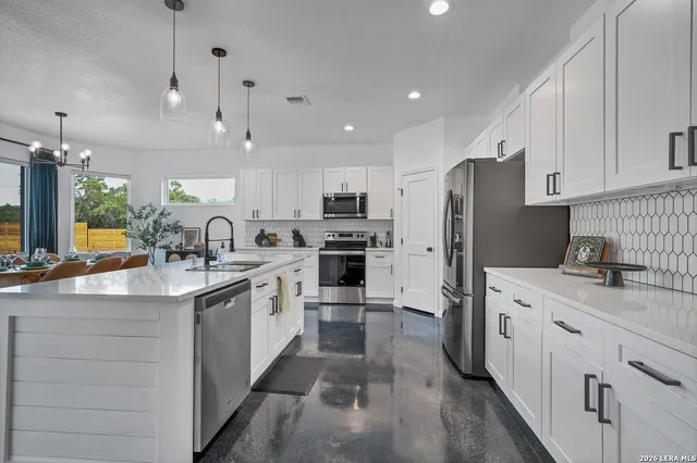 a kitchen with stainless steel appliances granite countertop a refrigerator a sink dishwasher a oven and a dining table with wooden floor