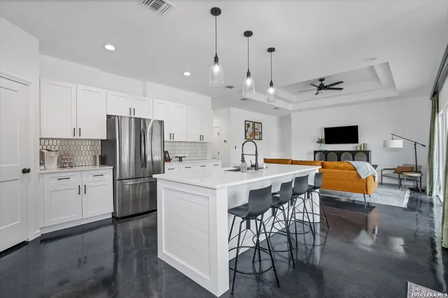 a kitchen with stainless steel appliances kitchen island granite countertop a dining table chairs refrigerator and sink