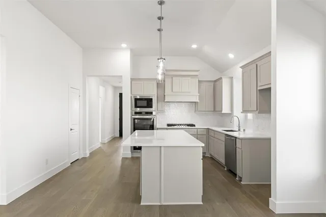 a large white kitchen with lots of counter space wooden floor and stainless steel appliances