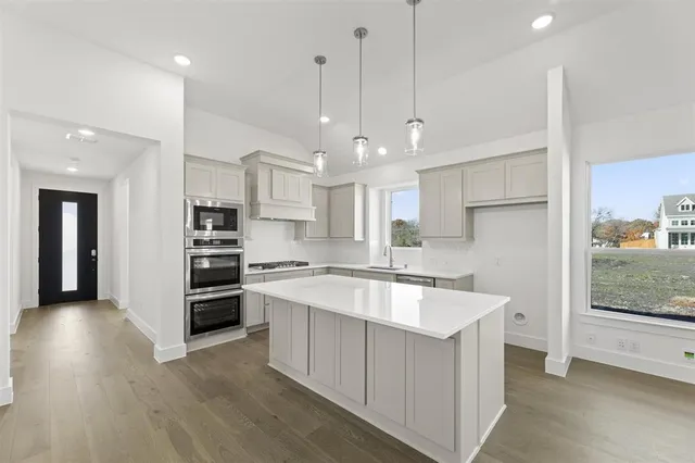a large kitchen with kitchen island a sink appliances and cabinets