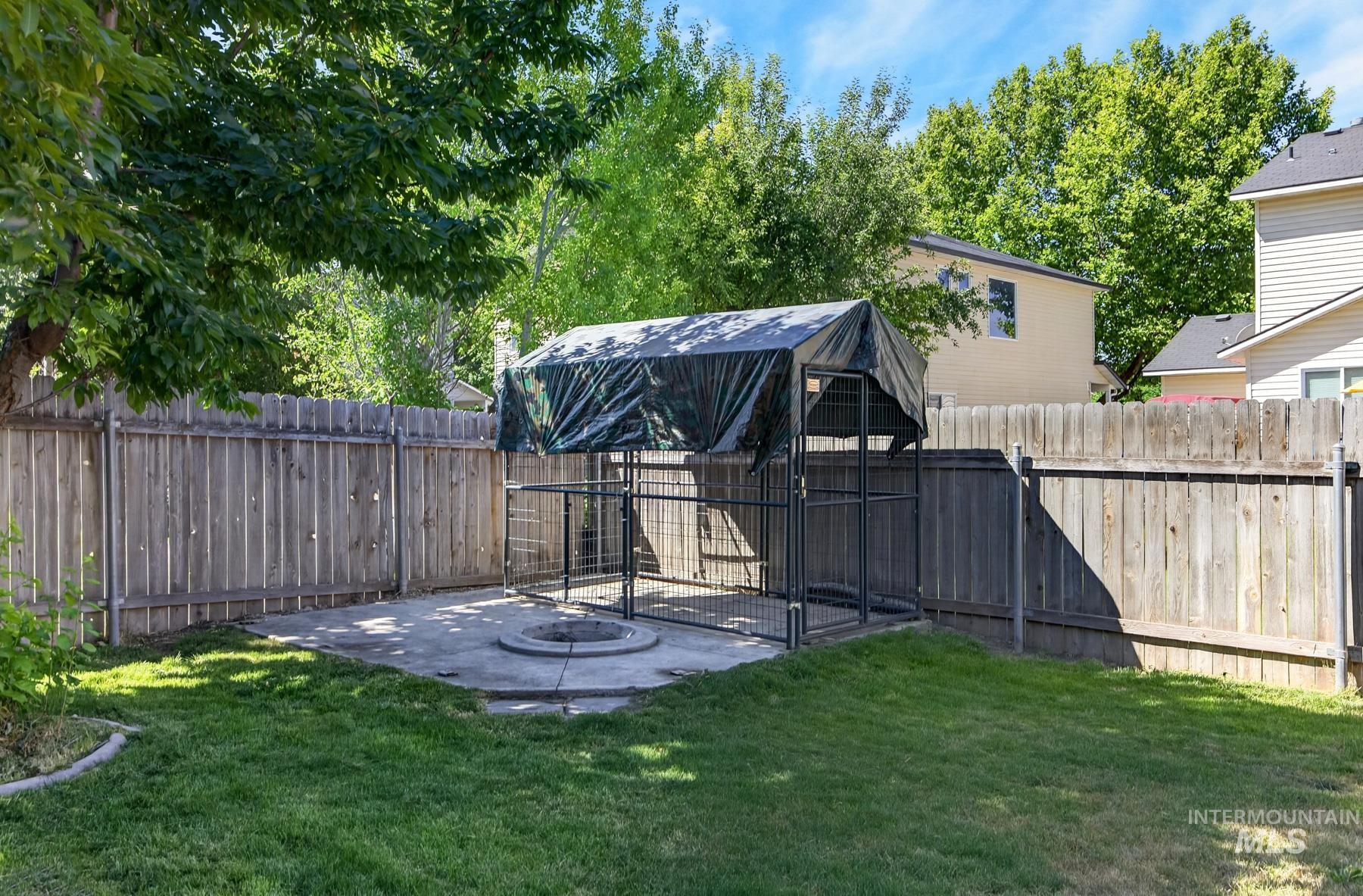 5020 Northrup Way Caldwell, ID 83607 - Photo 36 of 36 Expansive backyard featuring a manicured lawn, a wood fence, mature trees, and a concrete patio with a built-in fire pit