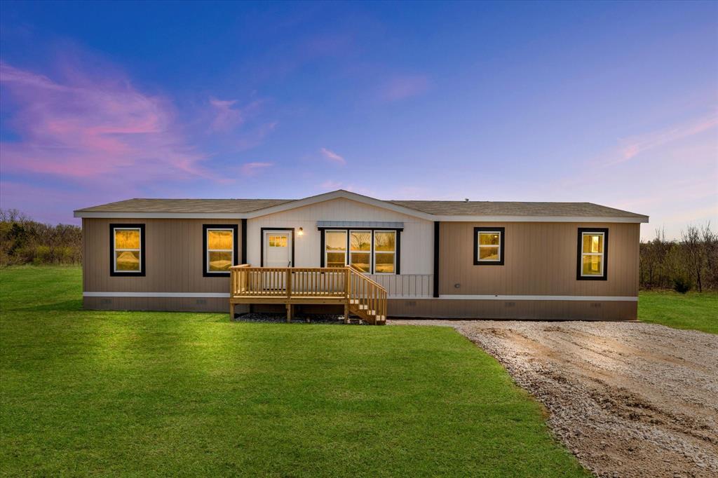 Back of property at dusk with crawl space, roof with shingles, a deck, and a lawn
