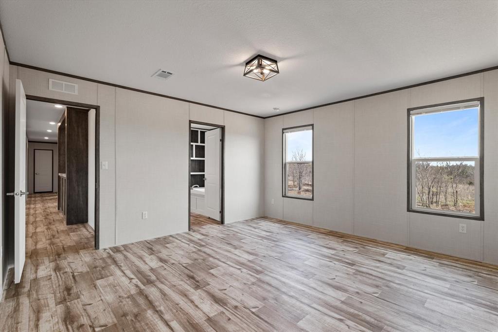 3924 Sandusky Road Whitesboro, TX 76273 - Photo 18 of 40 Unfurnished bedroom featuring multiple windows, light wood-style floors, and visible vents
