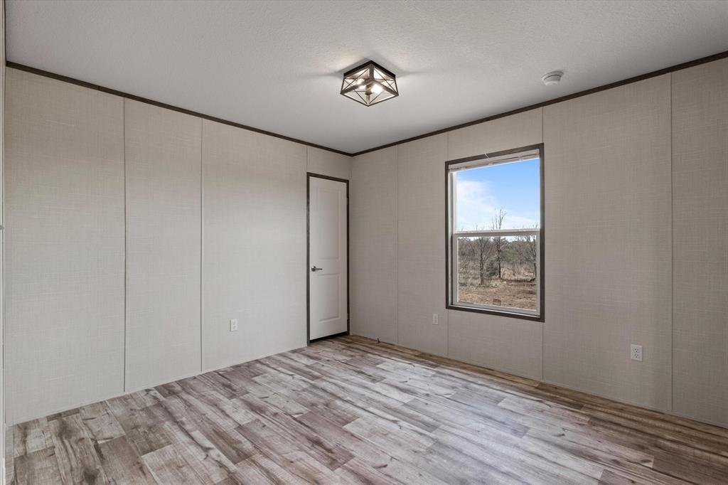 3924 Sandusky Road Whitesboro, TX 76273 - Photo 25 of 40 Unfurnished room featuring wood finished floors, ornamental molding, and a textured ceiling