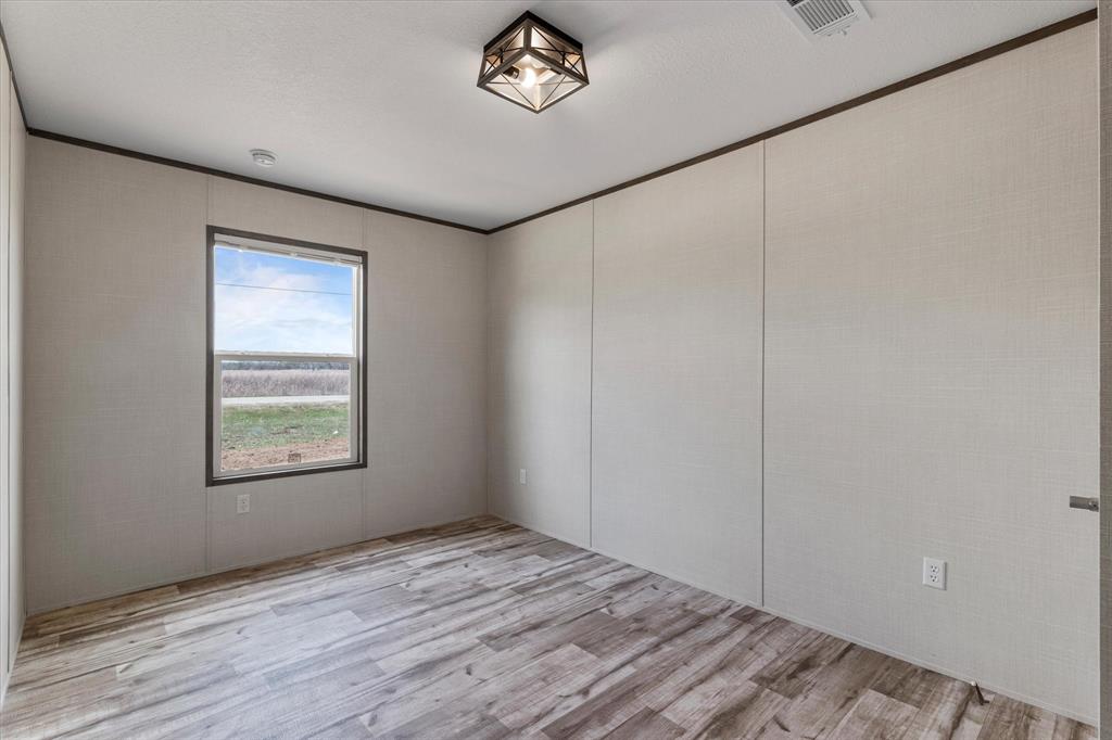 3924 Sandusky Road Whitesboro, TX 76273 - Photo 27 of 40 Spare room with visible vents, light wood-style flooring, and ornamental molding