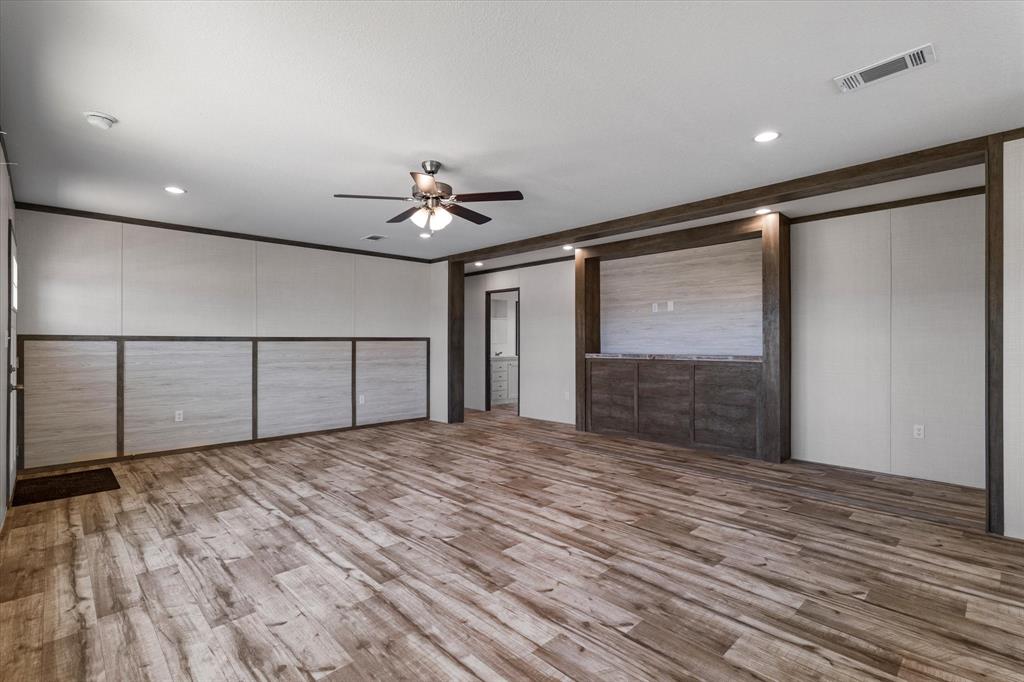 3924 Sandusky Road Whitesboro, TX 76273 - Photo 7 of 40 Unfurnished bedroom featuring a decorative wall, visible vents, crown molding, wood finished floors, and a ceiling fan