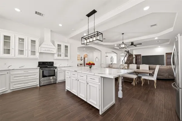 a kitchen with stainless steel appliances granite countertop a sink dishwasher a stove and a dining table with wooden floor