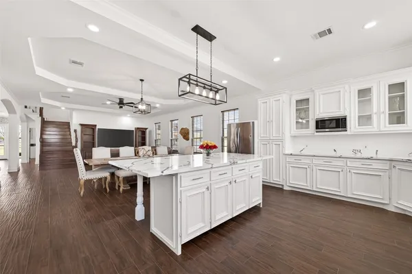 a large white kitchen with lots of counter space a sink appliances and living room view